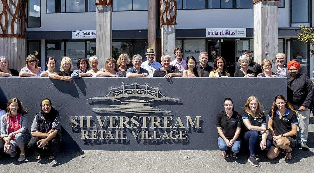 staff from Silverstream retail village shops standing by the village sign