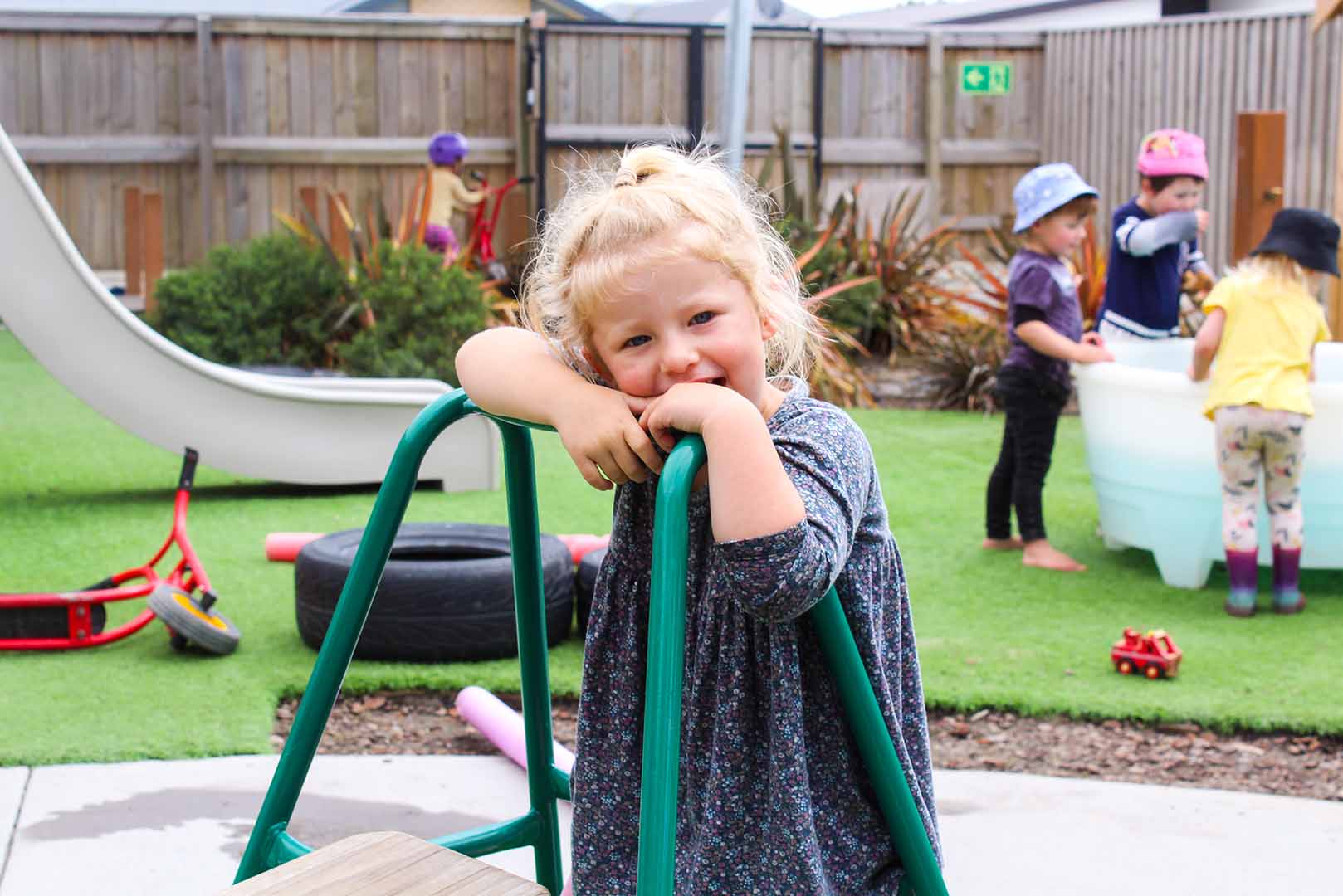 a young girl leaning on a climbing frame in the outdoor play space at Beststart Preschool