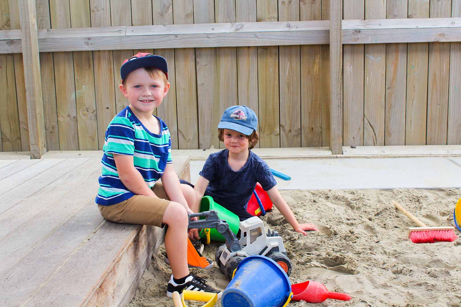 two young boys playing with sand toys in a sandpit