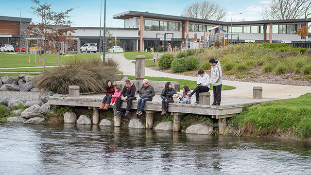 Family sitting on the jetty by the Silverstream river